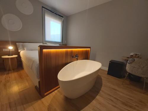a bathroom with a bath tub in front of a bed at Habital Suites in Jaca