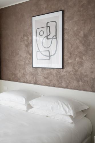 a framed picture above a bed with white pillows at Arca Guest House in San Trovaso
