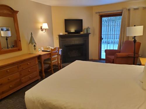 a hotel room with a bed and a desk and a television at Homestead Suites - Fish Creek in Fish Creek