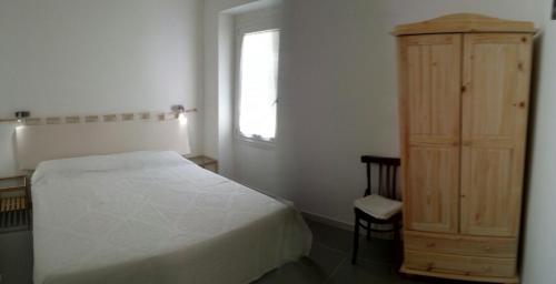1 dormitorio con 1 cama y armario de madera en Josso House, en Sorso