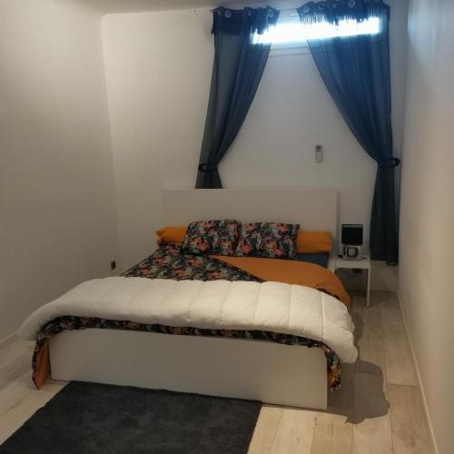 Ce lit se trouve dans une petite chambre dotée de rideaux bleus. dans l'établissement appart cosy,calme à 2 pas du centre de montbrison, à Montbrison