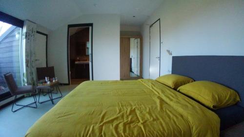 a bedroom with a large bed with yellow sheets at B&B In de Wei in Erp