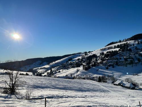 a snow covered hill with the sun in the sky at Cozy Condo, Ski in and Out in Todtnau