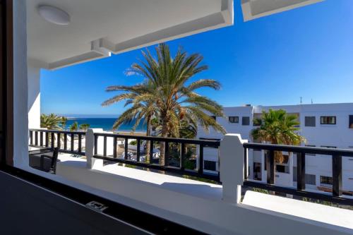 a balcony with a view of the beach and palm trees at Costa Luz Sirens Beach in Los Pocillos