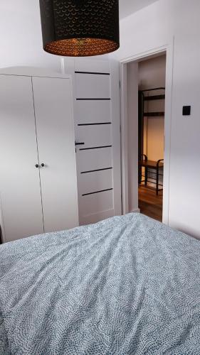 a white bedroom with a bed and a dresser at Apartamenty Obidowa in Obidowa