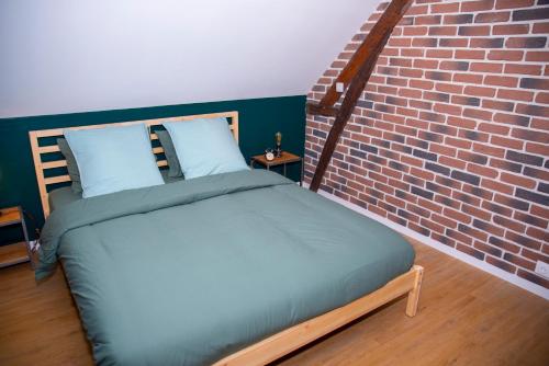 a bed in a room next to a brick wall at L'Atelier Brainois - Meublé de tourisme 3*** in Braine