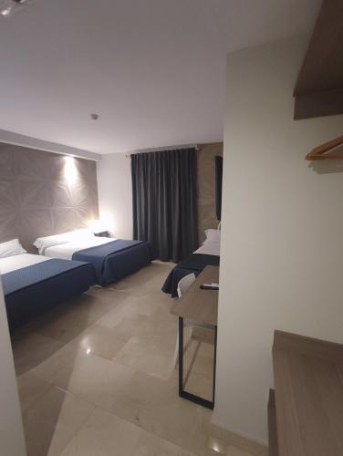 a hotel room with two beds and a table at Hotel Ciudad de Navalcarnero in Navalcarnero