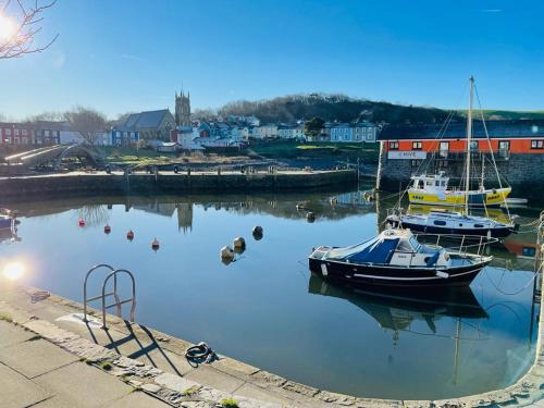 two boats are docked in the water in a harbor at Arosfa Harbourside Aberaeron in Aberaeron