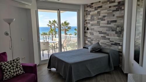 トロクス・コスタにあるEstudio FARO TORROX-1ª línea playaのベッドルーム1室(ベッド1台付)、海を望むバルコニーが備わります。