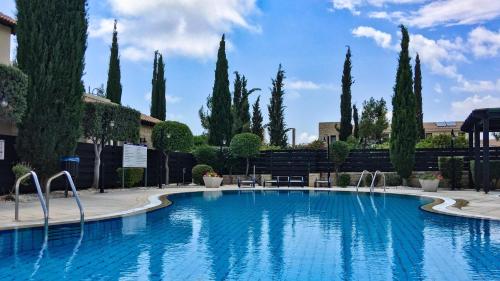 a large swimming pool with trees in the background at Aphrodite Hills Adonis Apartment in Kouklia