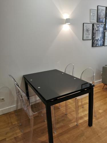 une table noire avec quatre chaises dans une pièce dans l'établissement Ô Cœur de Troyes - Bulles & Spa 4 étoiles, à Troyes