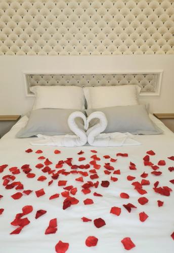- un lit avec des pétales de rose rouge et deux cœurs dans l'établissement Ô Cœur de Troyes - Bulles & Spa 4 étoiles, à Troyes