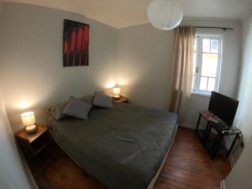 a bedroom with a bed with two lamps and a window at Escarabajo Hostel in Valparaíso