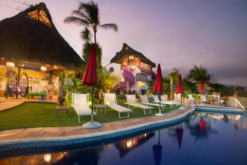 a group of chairs and umbrellas next to a pool at Villa Bella Bed & Breakfast Inn in Cruz de Huanacaxtle