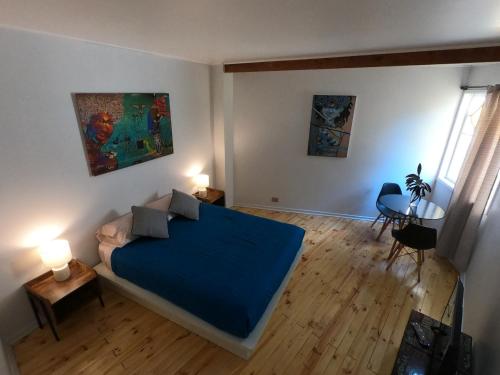 een slaapkamer met een bed met een blauwe deken bij Escarabajo Hostel in Valparaíso