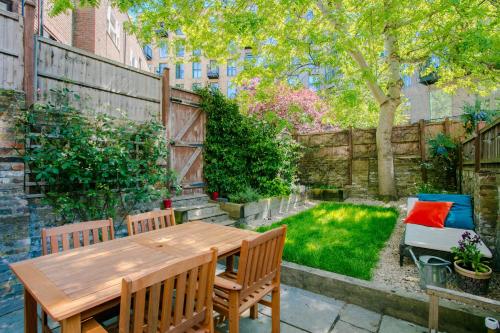 a backyard with a wooden table and chairs and a fence at Modern Garden Apartment Camden in London