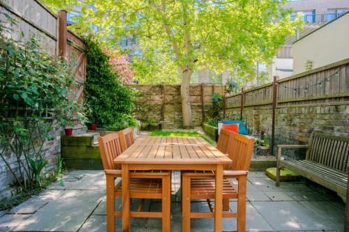 a wooden table and chairs in a garden at Modern Garden Apartment Camden in London