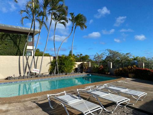 a swimming pool with lounge chairs and palm trees at Paradise at Ehupua in Honolulu
