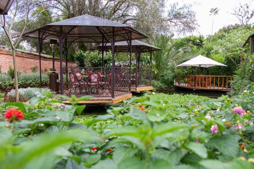 a gazebo in a garden with flowers at Rukka Lodge in Tumbaco