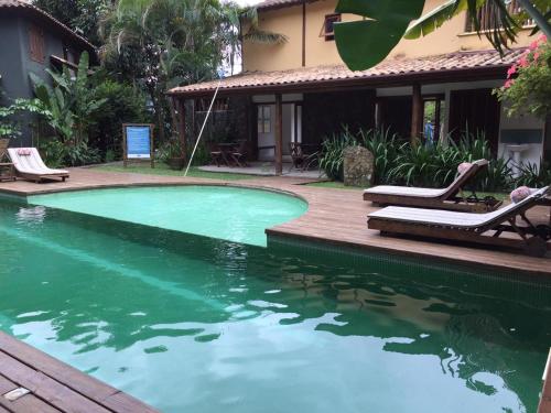 a swimming pool with two lounge chairs next to a house at Estúdio no Condomínio Acquaville in Ilhabela
