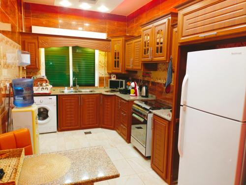 uma cozinha com armários de madeira e um frigorífico branco em Maria Home em Madaba