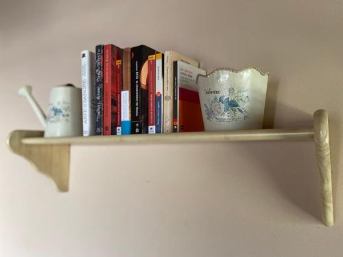 un estante con libros y tazas en una pared en La Almenara, en Aracena