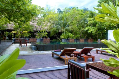 a patio area with chairs, tables, and benches at The Sevenseas Resort Koh Kradan in Koh Kradan