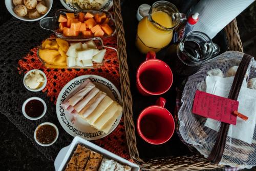 uma mesa com queijo e outros alimentos e bebidas em Pousada Refúgio dos Pássaros na Praia do Rosa