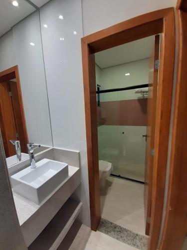 a bathroom with a sink and a toilet and a mirror at Ilhéus North Residence Danilo in Uruçuca