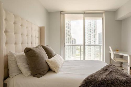 - une chambre avec un grand lit blanc et une grande fenêtre dans l'établissement Downtown Miami Condo at the W - ICON Brickell, à Miami