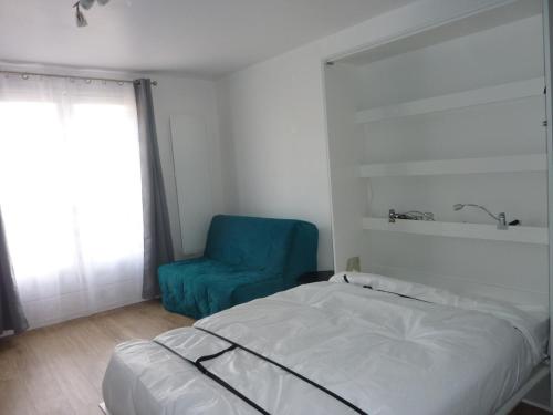 um quarto com uma cama e uma cadeira azul em Studio bord de mer en résidence MERVILLE FRANCEVILLE PLAGE em Merville-Franceville-Plage