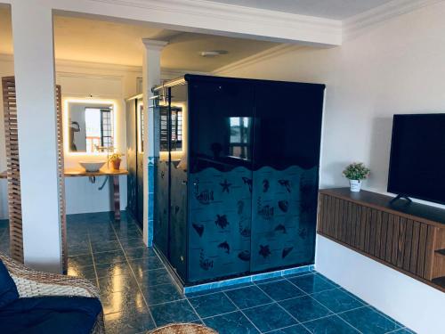 a blue cabinet in a living room with a tv at Suíte frente mar e pés na areia in Japaratinga