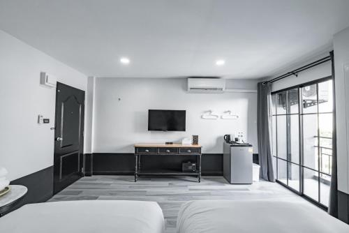 a bedroom with a bed and a tv on a wall at Blu Monkey Boutique Bangsaen in Ban Hua Khao Sammuk