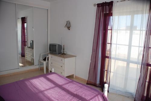 1 dormitorio con 1 cama, TV y espejo en Terraço e Mar, en Alvor