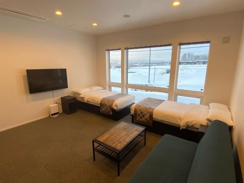 a room with two beds and a flat screen tv at Pensione UNO in Niseko