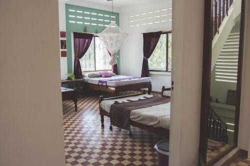 a room with two beds and a table and windows at The Playground in Kampot