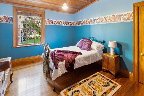 a blue bedroom with a bed and a window at Headlands Estate in Whanganui