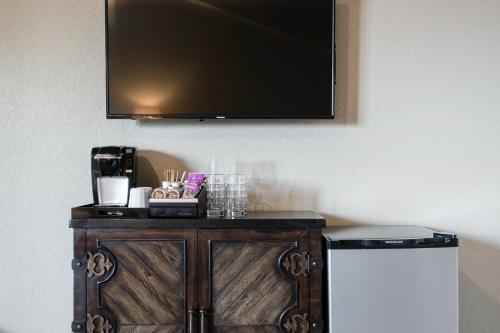 a television on a wall above a table with a coffee maker at Century Oak House in Spring Branch