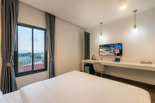 a hotel room with a bed and a desk and a window at Nine River Hotel in Ratchaburi