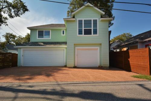 a green house with two garage doors on a driveway at Willow House Unit B in Austin