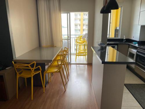 eine Küche mit einem Tisch und gelben Stühlen in einem Zimmer in der Unterkunft Excelente apartamento pé na areia in Barra Velha