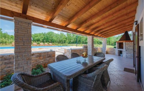 patio z drewnianym stołem i krzesłami oraz basenem w obiekcie Three-Bedroom Holiday Home In Katun w mieście Katun