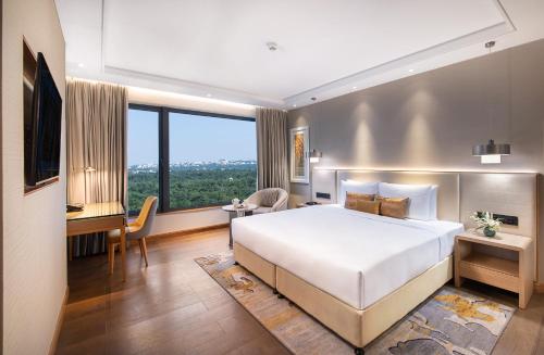 a bedroom with a large white bed and a desk at Vivanta Bhubaneswar DN Square in Bhubaneshwar