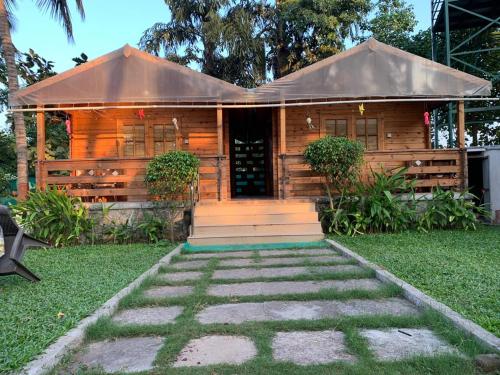 a small wooden house with a pathway leading to it at Casa de Kihim in Alibaug