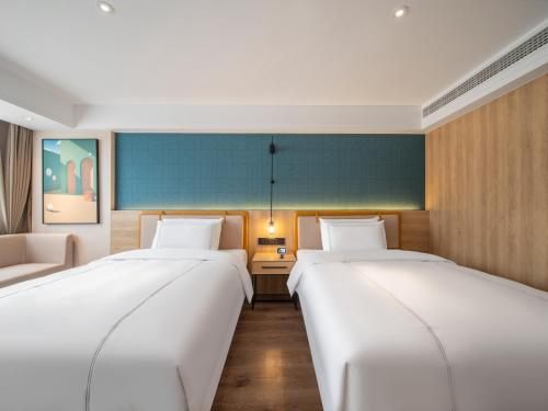 a room with two beds and a couch in it at 银座佳悦精选（菏泽郓城水浒城店） in Yuncheng