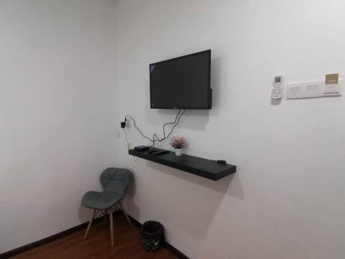 a room with a chair and a television on a wall at Hi TechSTAY in Lunas