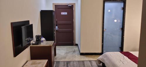 a room with a bed and a television and a door at The Jamun Tree in Muzaffarpur