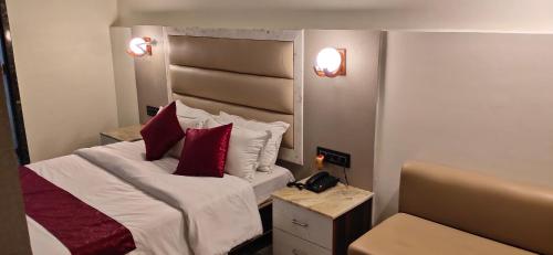a bedroom with a bed with red pillows and a telephone at The Jamun Tree in Muzaffarpur