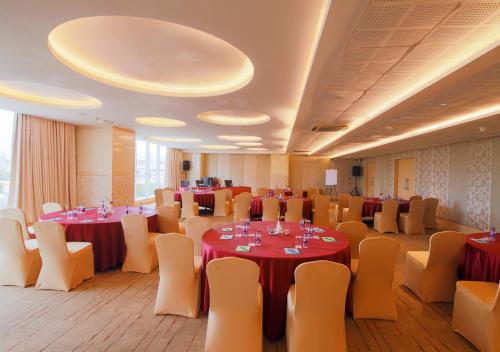 a banquet hall with tables and chairs with red table cloth at E Hotel in Chennai