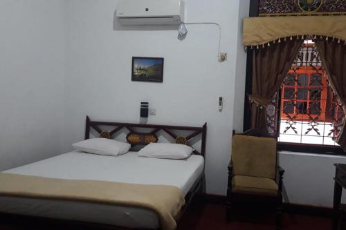 a bedroom with a bed and a chair and a window at KoolKost At Tenggilis - Minimum Stay 30 Nights in Tenggilismedjojo